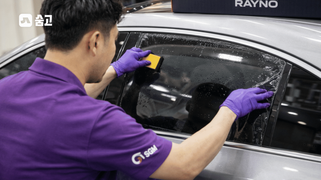 RAYNO 필름을 정밀하게 유리창에 시공 중인 기술자